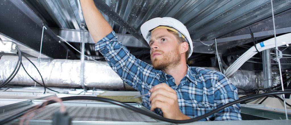 A craftsman wiring in the ceiling